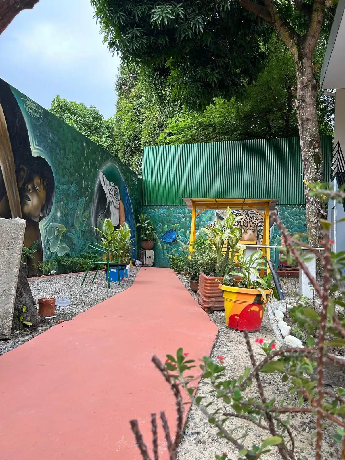 Caminho vermelho entre canteiros e muro pintado